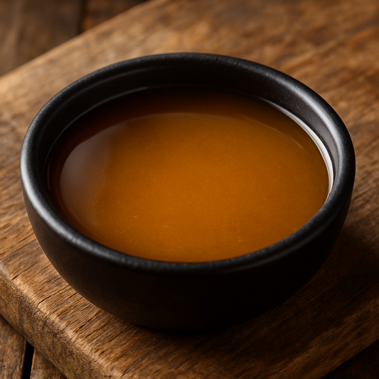 lighter vinegar bbq sauce in small black bowl on top of wood cutting board 